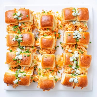 Hot Buffalo Chicken Pizza Dip Sliders are pulled apart to show melted cheese and chicken.