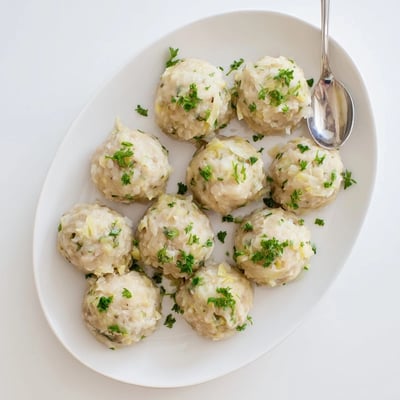Golden German Cabbage Dumplings simmer in savory broth, ready to serve with melted butter and creamy mushroom sauce on the side.